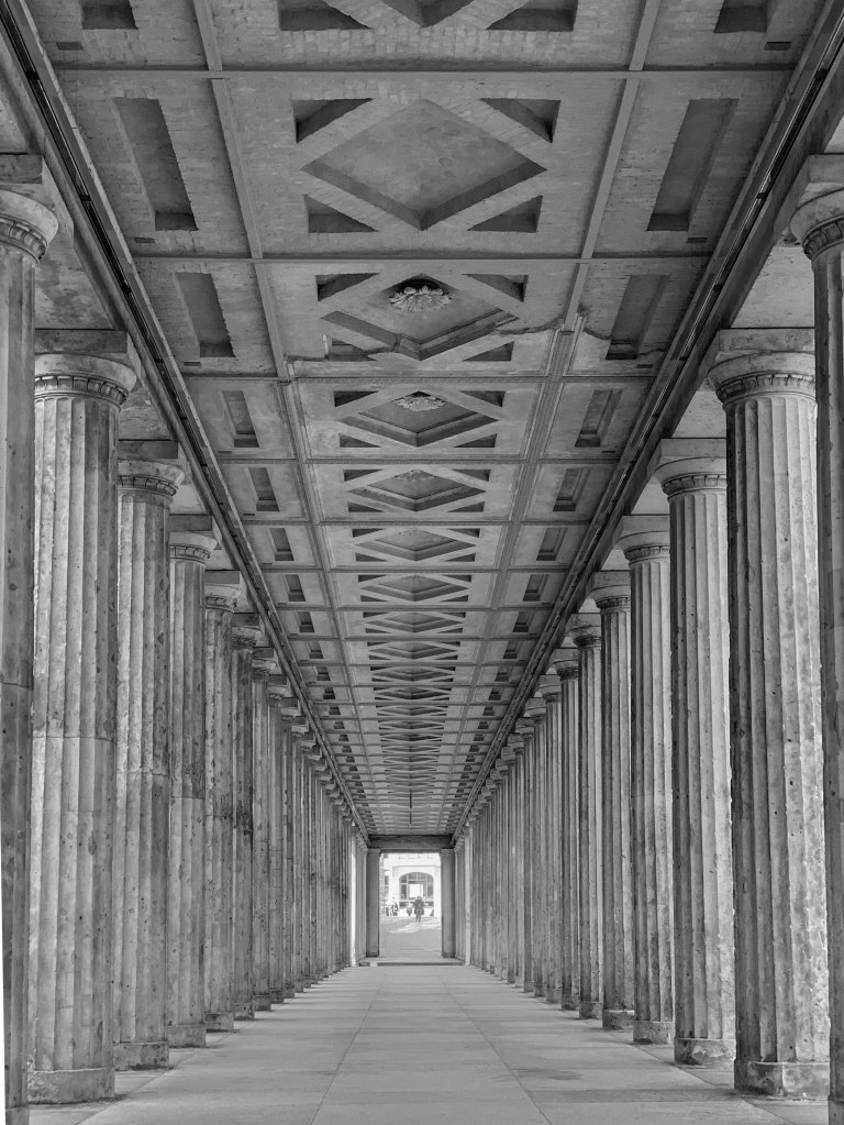 Long colonnaded passage on Museum Island, with repeated columns and a bright opening at the far end.