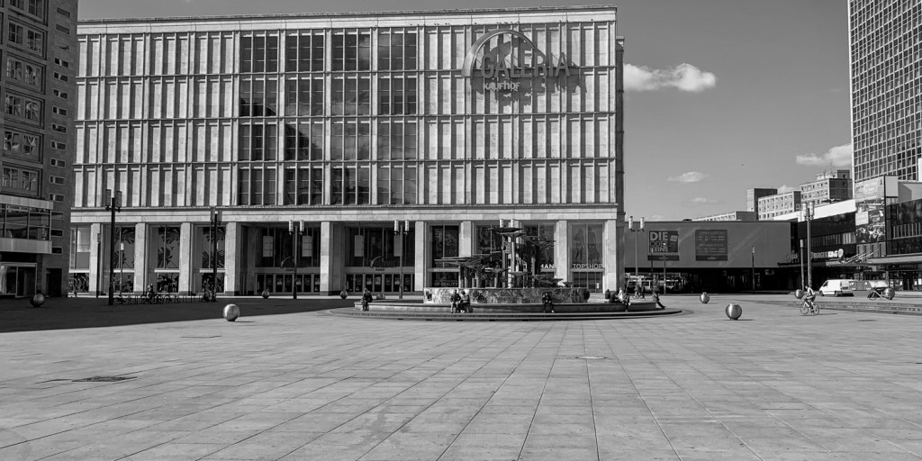Large modern building on an empty Berlin square, with glass façade and open paving.