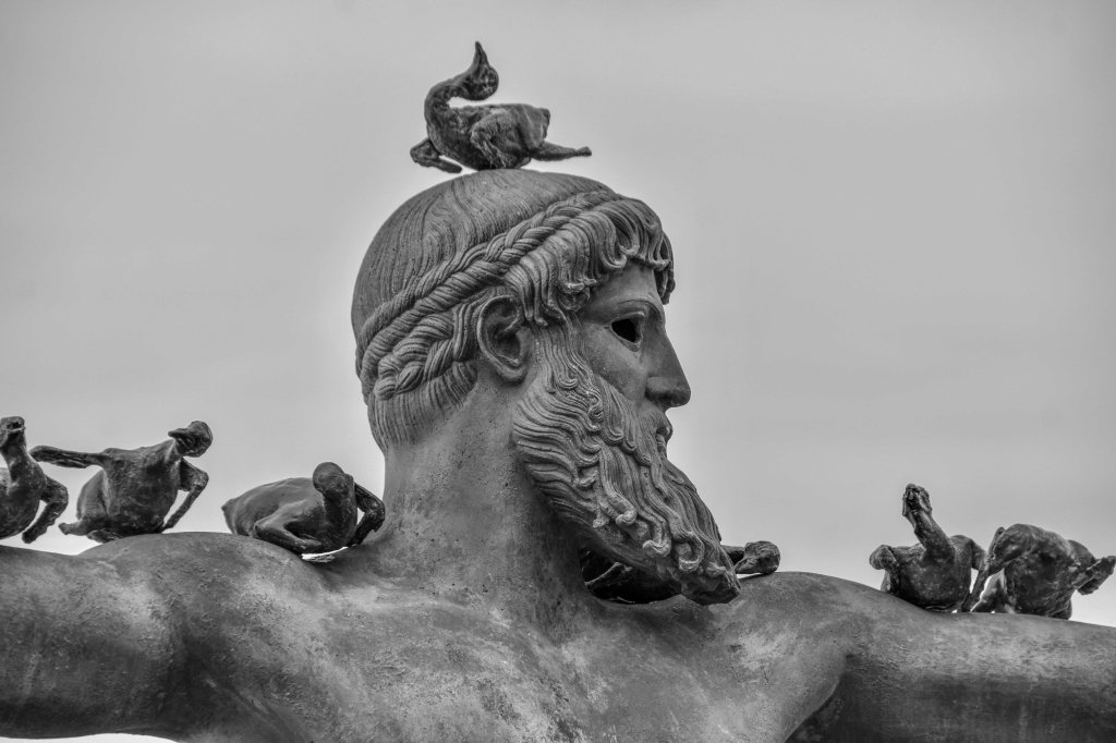 Close view of a large seaside statue with birds resting on its head, shoulders, and arms.