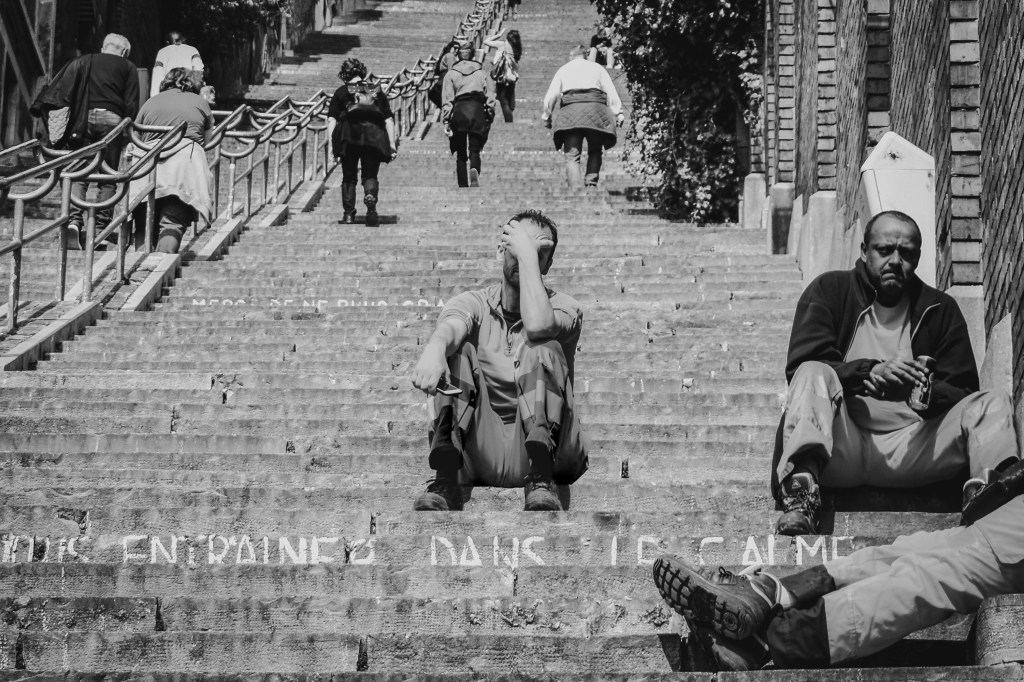 People sitting, resting, and moving on a broad outdoor staircase.