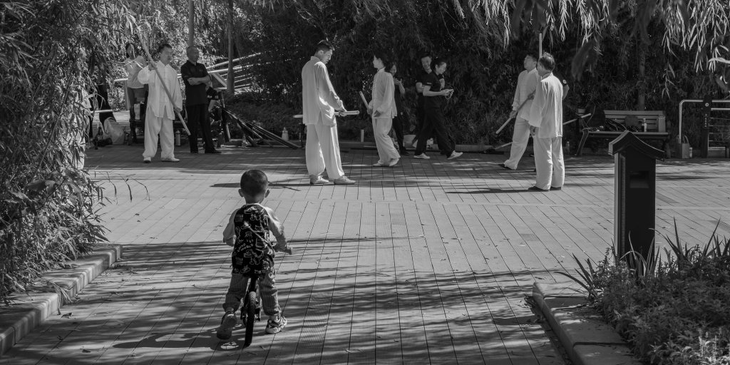 Child watching adults practise in a park or public square.