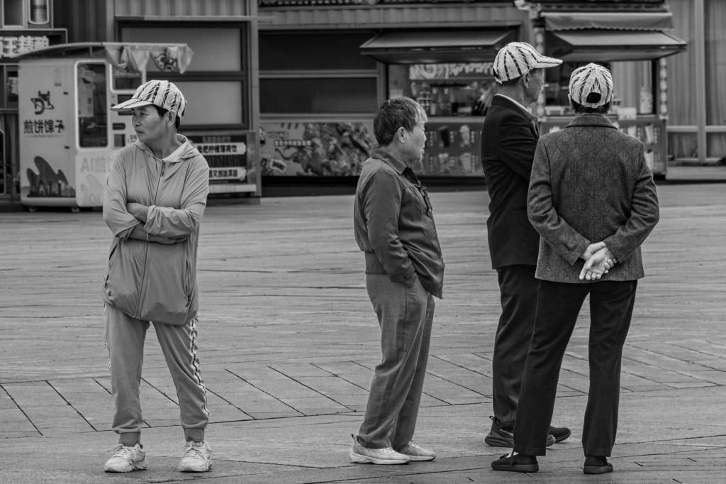 Four people standing, looking in different directions in Beijing.