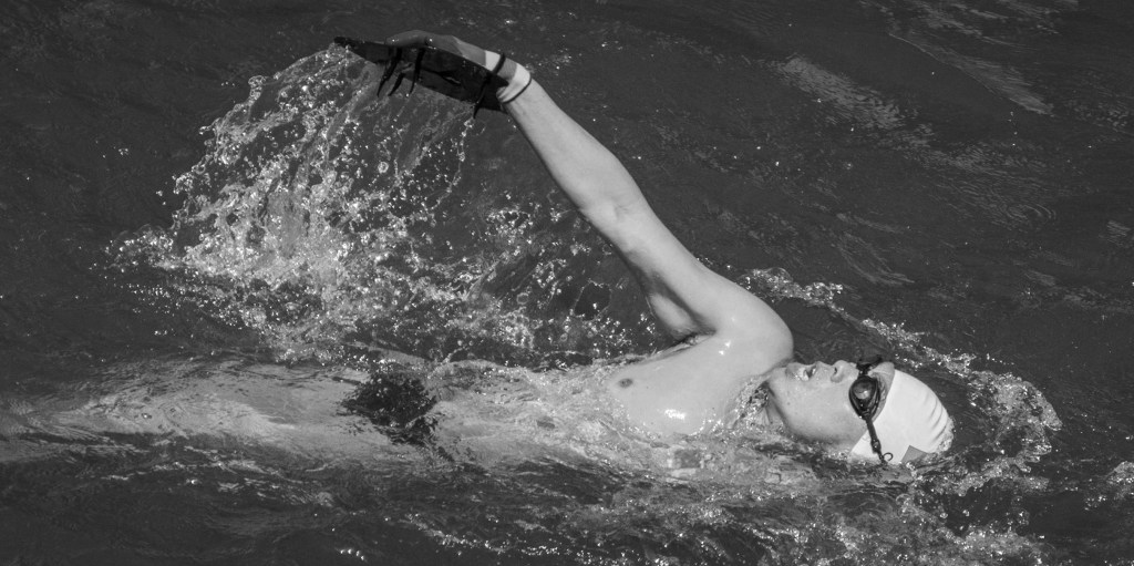 Swimmer doing front crawl in dark water.