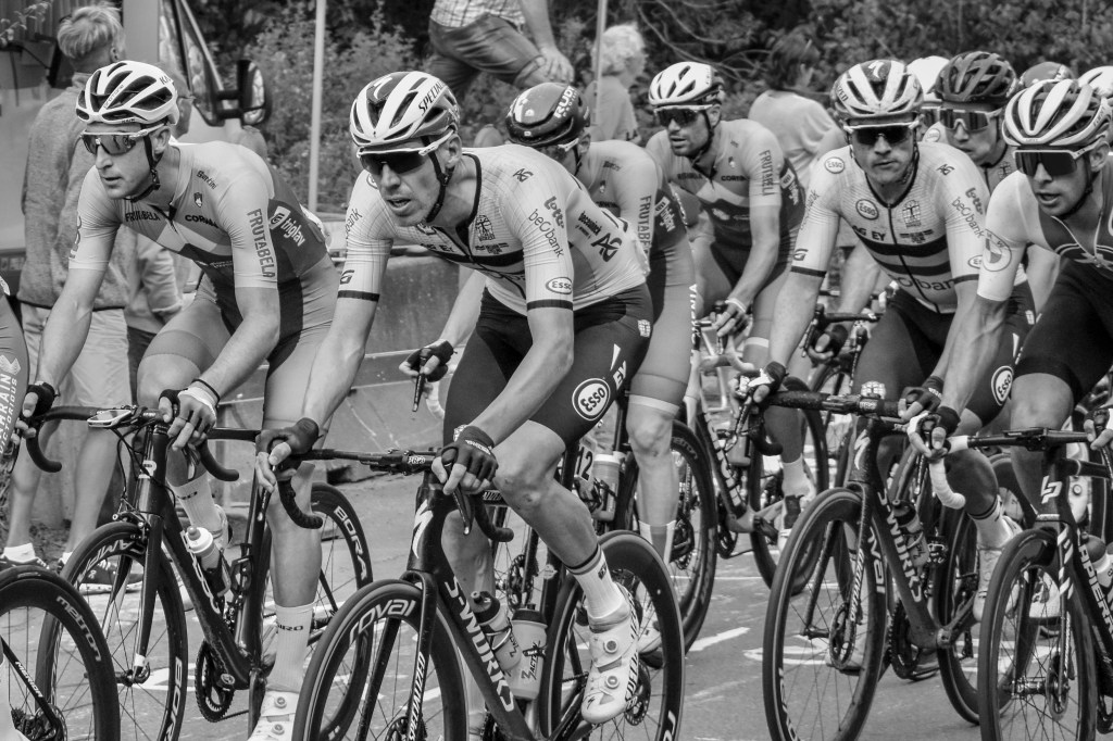 Cyclists passing spectators and a flag during the UCI Leuven 2021 race.