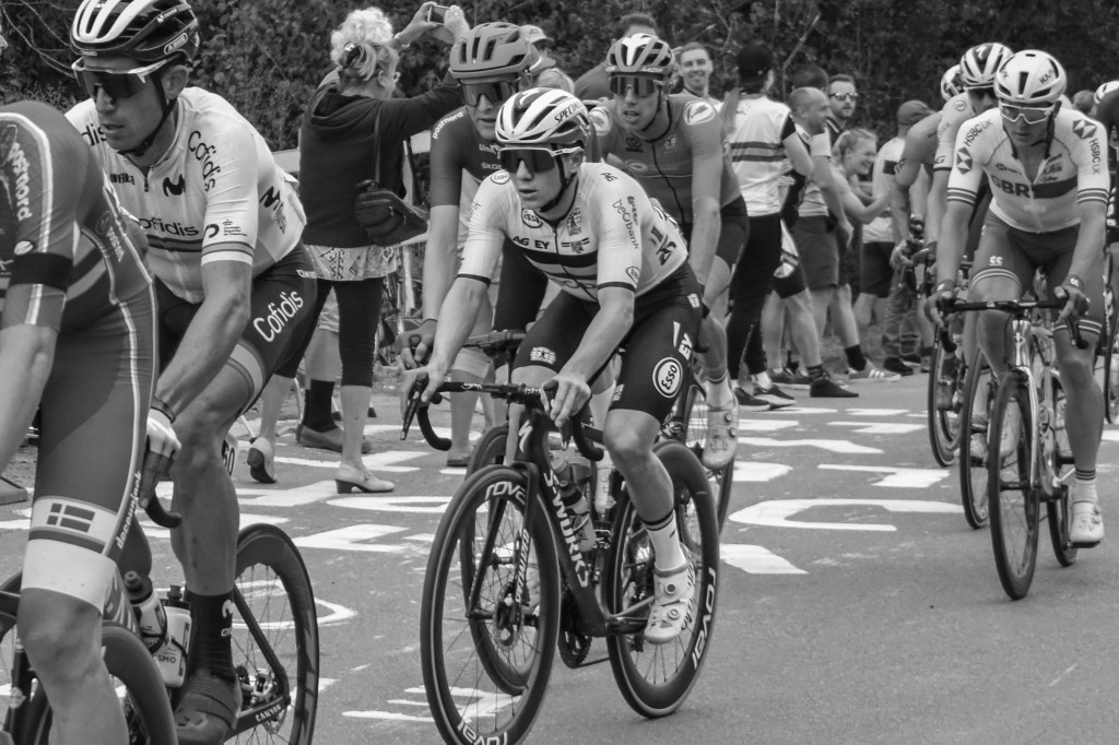 Cyclists passing through a crowded section of road, with spectators pressed along the roadside.