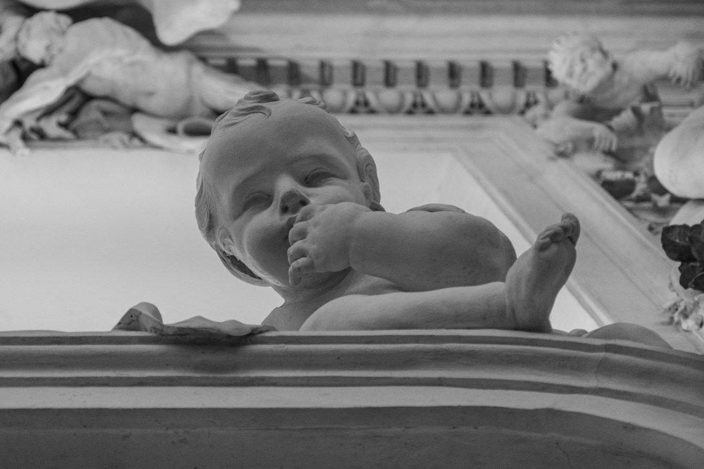 Sculpted cherub on a church ceiling, seen from below.