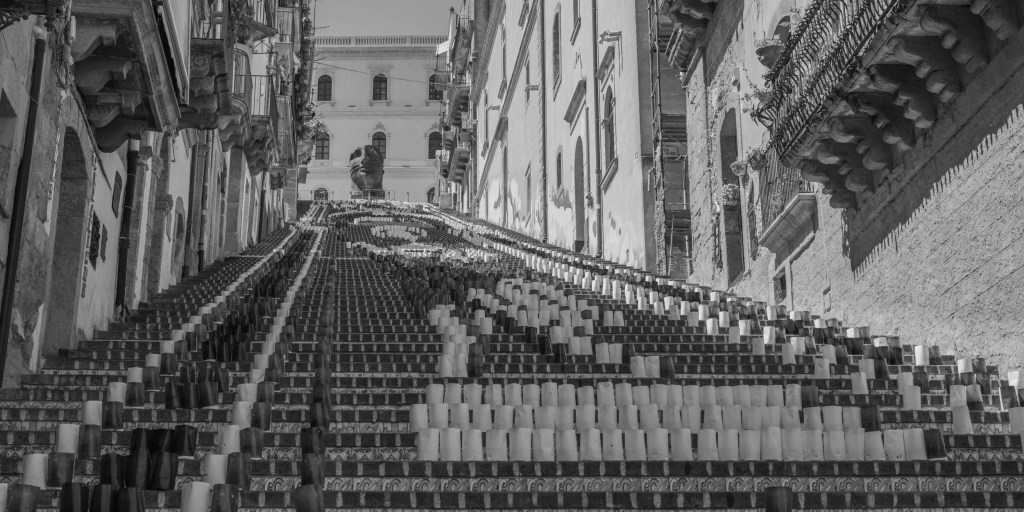 The monumental staircase rises between buildings, covered with rows of light and dark cylindrical lanterns arranged in patterns.