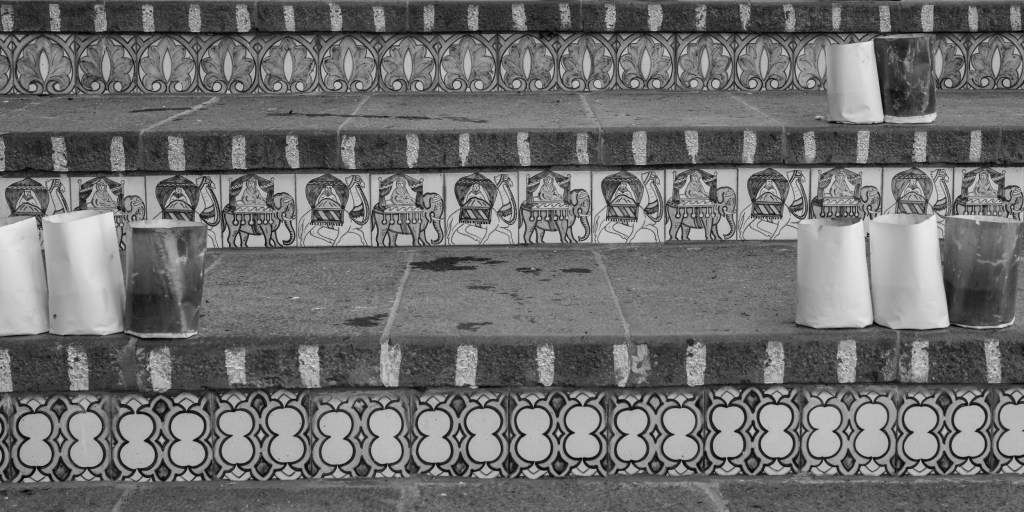 A close view of decorated stair risers shows repeating ceramic designs and rows of cylindrical lanterns.