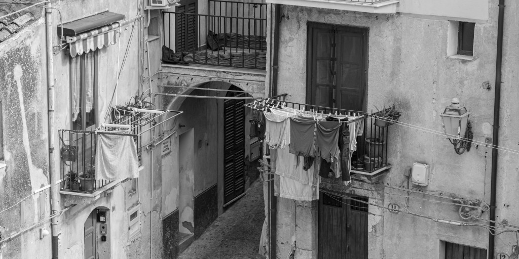 Laundry hangs across balconies above a narrow street of weathered houses.