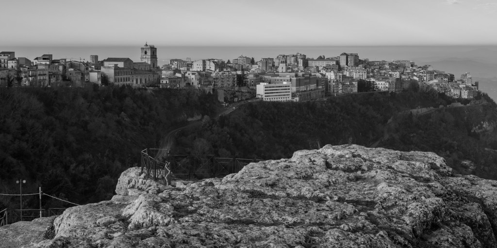 Enna stretches along a high ridge beyond a broad rocky outcrop in the foreground.