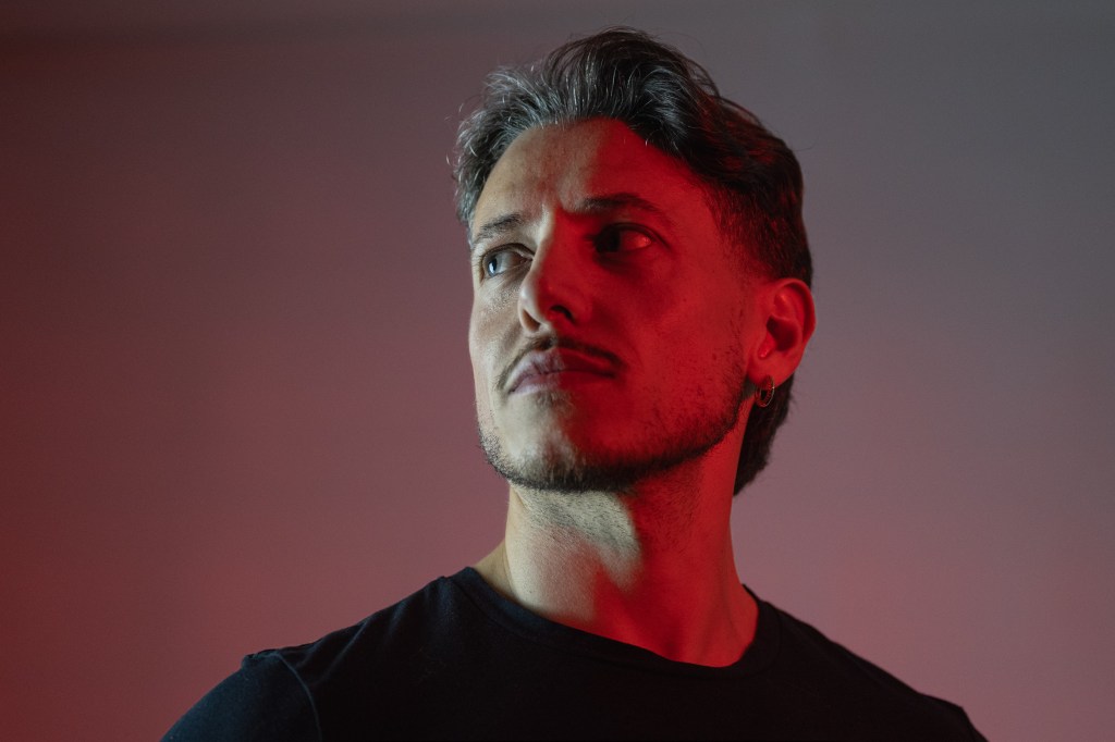 Close portrait of a man looking upward, his face divided by red and neutral light.